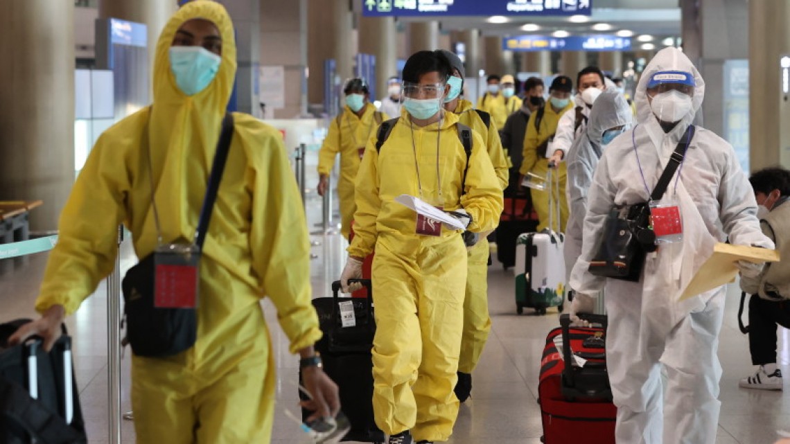 Pasageri cu echipamente de protecție pe Aeroportul Incheon din Coreea de Sud