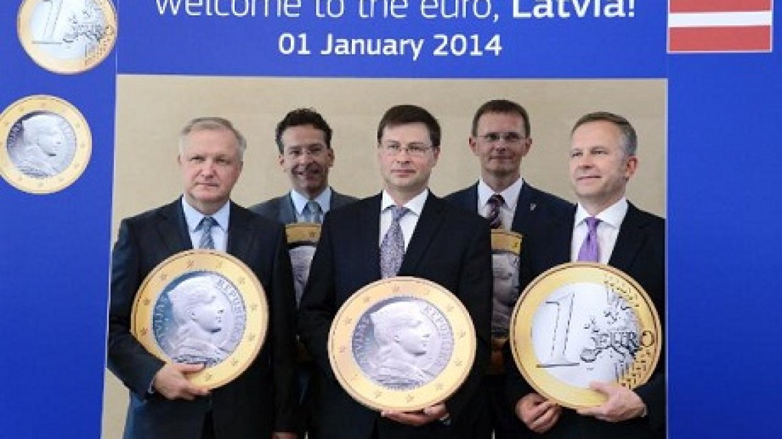 Intrarea Letoniei în zona euro/ Foto: Comisia Europeană. Olli Rehn, Jeroen Dijsselbloem, Valdis Dombrovskis, Andris Vilks, Latvian Minister for Finance, and Ilmārs Rimšēvičs, Governor of the Bank of Latvia, all holding giant false 1 Euro coins at the effigy of Latvia (from left to right)